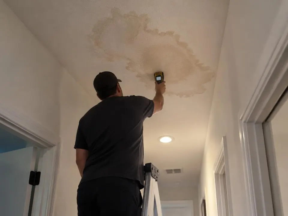 Generated illustration of a technician holding a moisture meter to a stained hallway ceiling